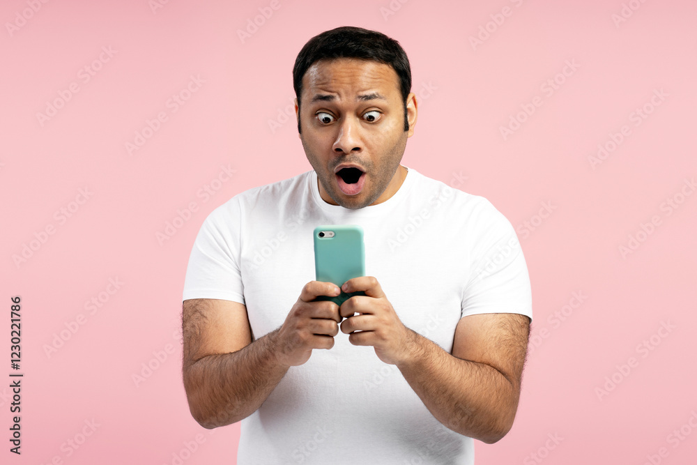 Shocked man reading news on smartphone on pink background Shocked man reading news on smartphone on pink background