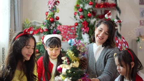 Mother and daughters joyfully decorating a Christmas tree at home, celebrating the holiday season with ornaments, costumes, and festive spirit.