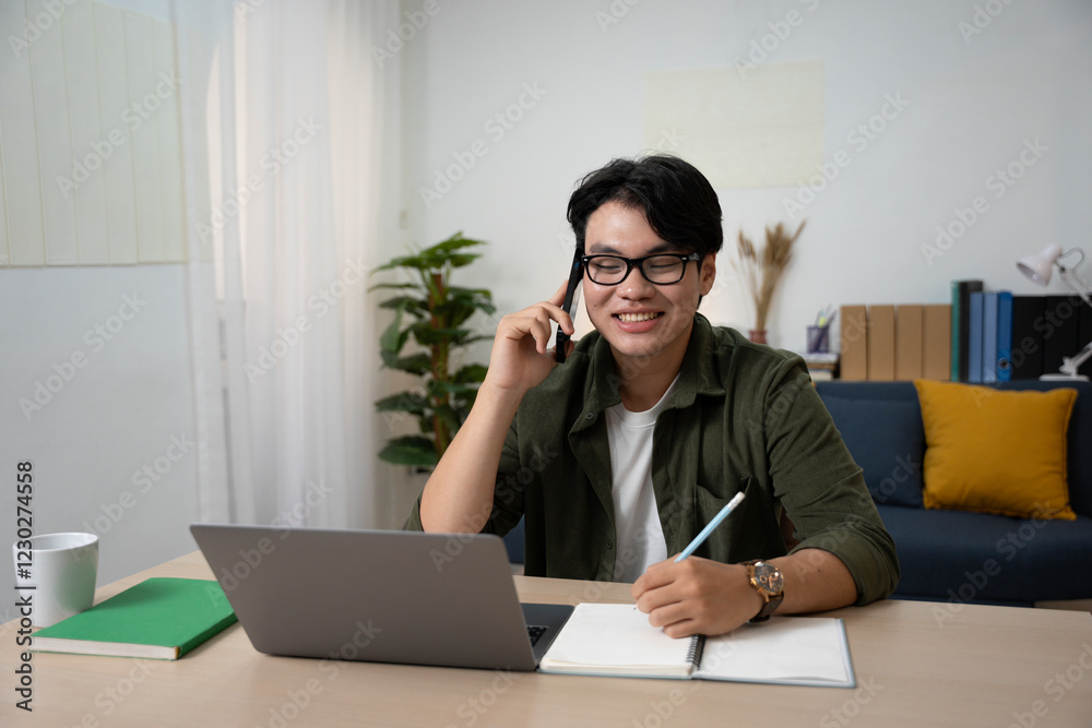 Handsome freelancer analyzing project online over laptop while working at dining table in home office Young man working at home. Home office. , freelance Handsome freelancer analyzing project online over laptop while working at dining table in home office Young man working at home. Home office. , freelance