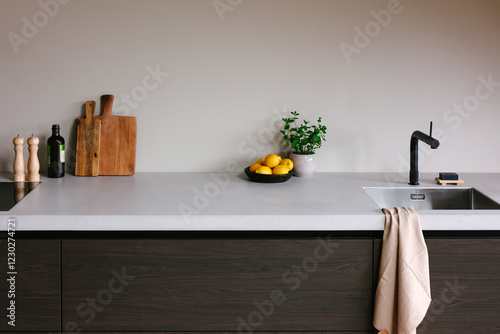 Modern kitchen counter with sink, bowl of lemons and wooden cutting board.