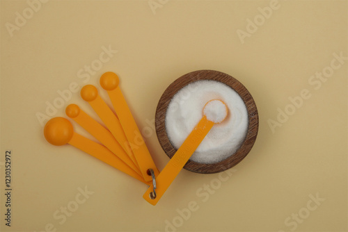 Gluconolactone in wooden plate with measuring spoons. Glucono Delta-Lactone, Pure GDL. White powder, oxidized derivative of glucose. Food additive E575. photo