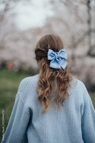 Girl in the garden with a blue bow on her hair