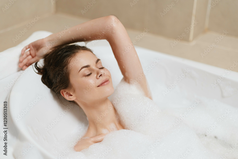 Relaxed young woman enjoying a bubble bath, closed eyes with a serene expression, hands raised, in a light-colored bathroom setting. Self-care and wellness concept. Relaxed young woman enjoying a bubble bath, closed eyes with a serene expression, hands raised, in a light-colored bathroom setting. Self-care and wellness concept.