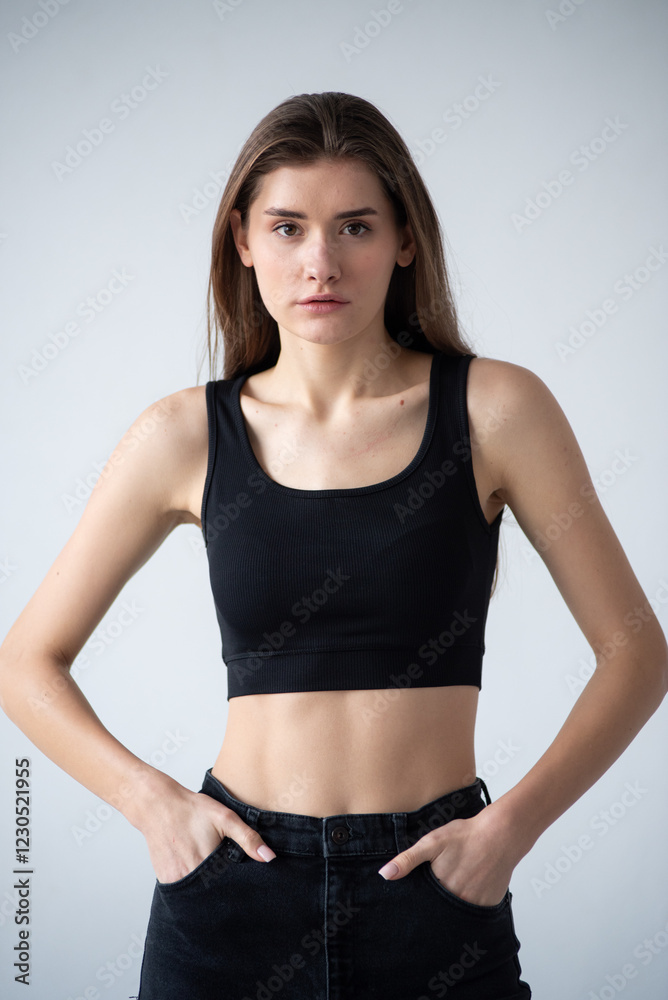 A professional modeling snapshot of a young female model in a black crop top and high-waisted jeans, posing against a textured gray wall. Capturing her natural elegance, toned physique, and confident A professional modeling snapshot of a young female model in a black crop top and high-waisted jeans, posing against a textured gray wall. Capturing her natural elegance, toned physique, and confident