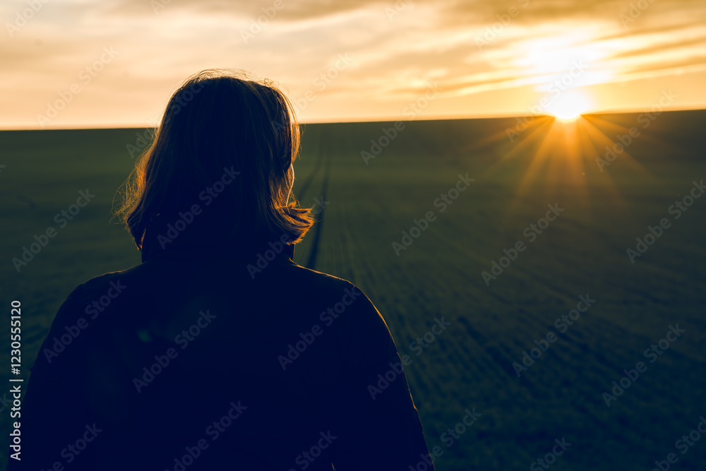 Fototapeta premium A girl contemplates the sunset in silence