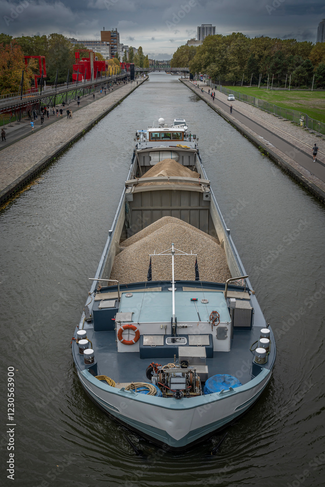 Paris, France - 10 20 2024: La Villette Park. View of the Saint-Denis Canal with a barge sailing from the Flander Bridge . Paris, France - 10 20 2024: La Villette Park. View of the Saint-Denis Canal with a barge sailing from the Flander Bridge .