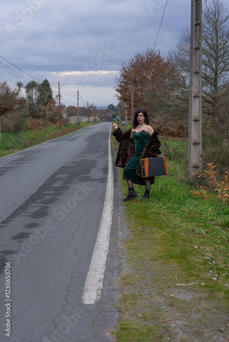 Woman on the side of a secondary road hitchhikes with her coat down