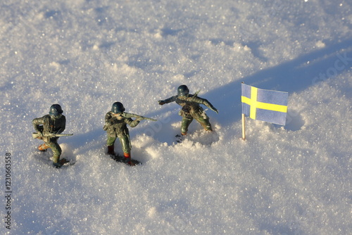 Small toy soldiers in the snow. Winter warfare concept. Defend the flag.