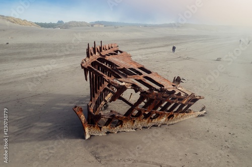 Rusty ship wreck on a foggy beach. Visitors observe the decaying vessel. Coastal scene. Wreck Of The Peter Iredale, Fort Stevens State Park, Oregon, USA