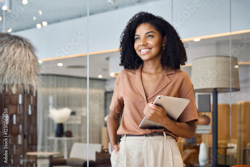 Happy confident young African American professional woman, female entrepreneur, businesswoman looking away holding tab standing in office at work dreaming of future success.
