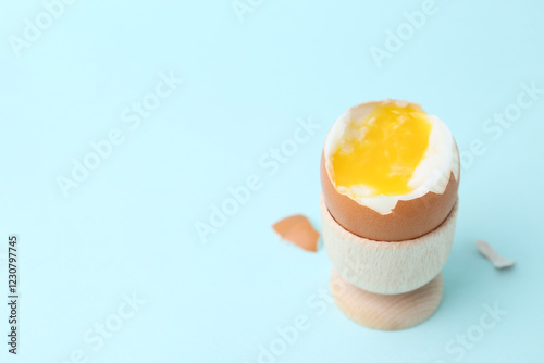 Foto Soft boiled egg in eggcup on light blue background, closeup