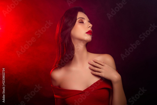 Elegant woman in red dress with sensual expression against dramatic red and black background