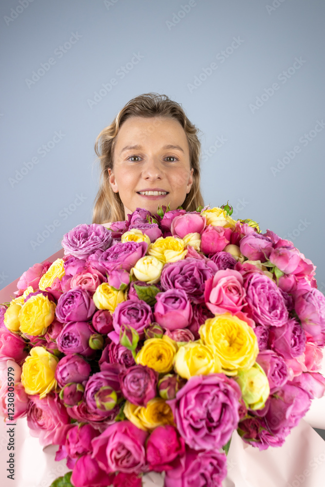 closeup gray background a young blonde girl with a large bouquet of pink peony roses women's holiday March 8 first date smiling closeup gray background a young blonde girl with a large bouquet of pink peony roses women's holiday March 8 first date smiling