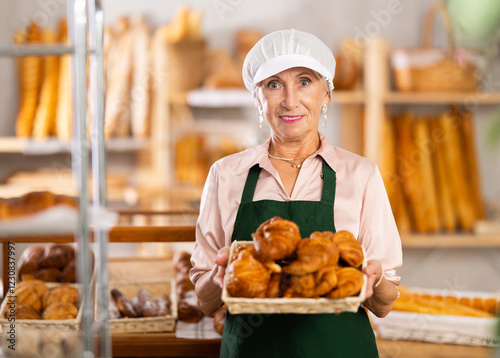 senior bakery worker sells croissants and shows off a variety of crescent-shaped buns. High quality photo photo