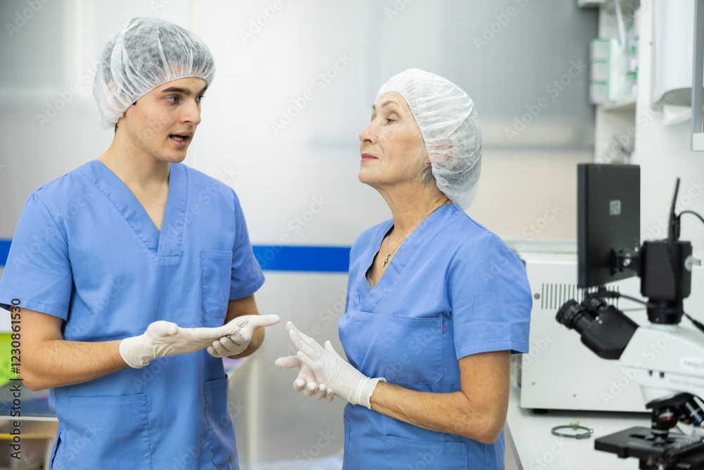 Obraz premium Two employees senior woman and young man of veterinary service communicate after receiving patient, discuss treatment regimen of complex clinical case