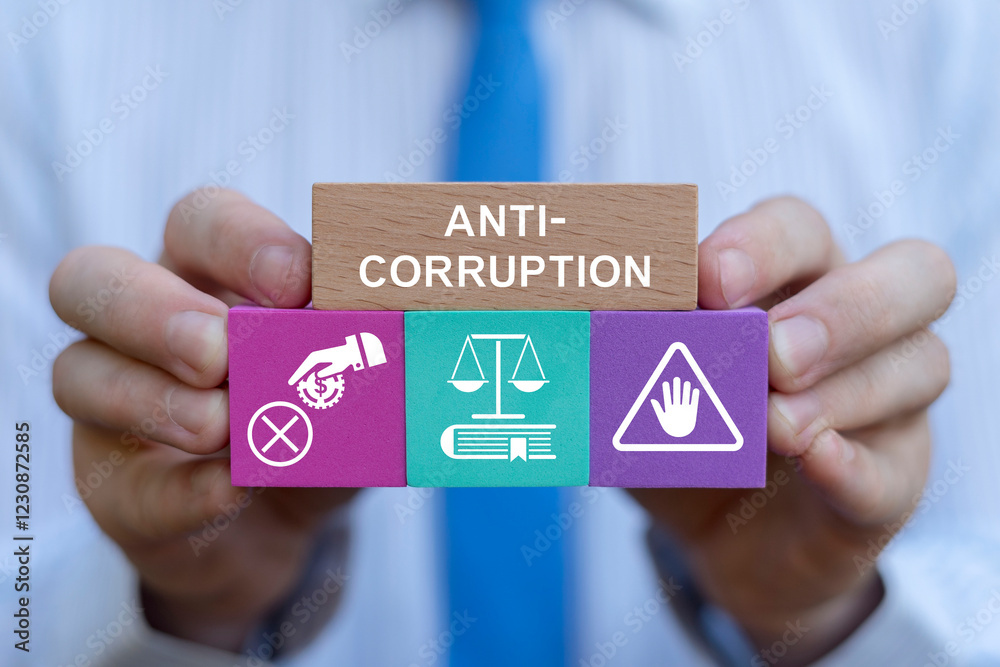 Business person holding colorful blocks with icons sees inscription: ANTI-CORRUPTION. Concept of anti corruption activities that oppose or inhibit corruption. International anti-corruption day.
