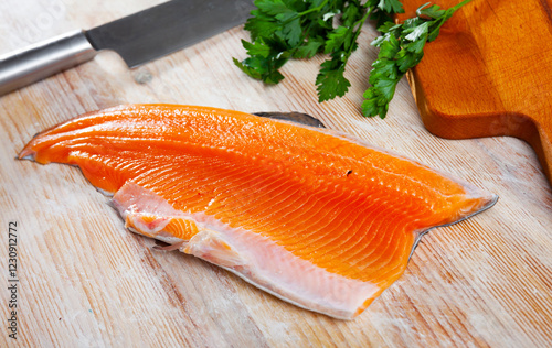 Uncooked fillet trout fish with parsley and garlic on wooden table