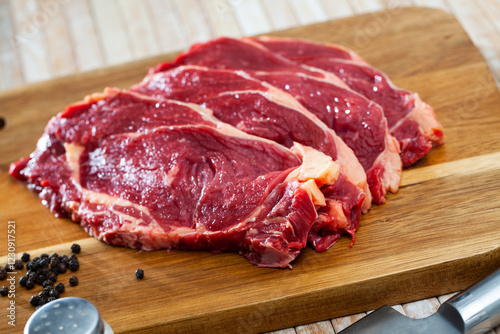 Pieces of raw boneless beef on wooden background with seasonings prepared for roasting ..