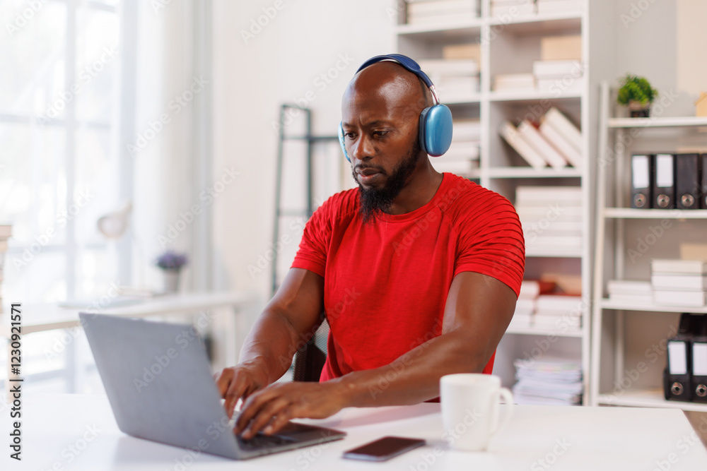 African American freelancer business man wearing headphones, enjoying working on laptop at workplace office. African American freelancer business man wearing headphones, enjoying working on laptop at workplace office.