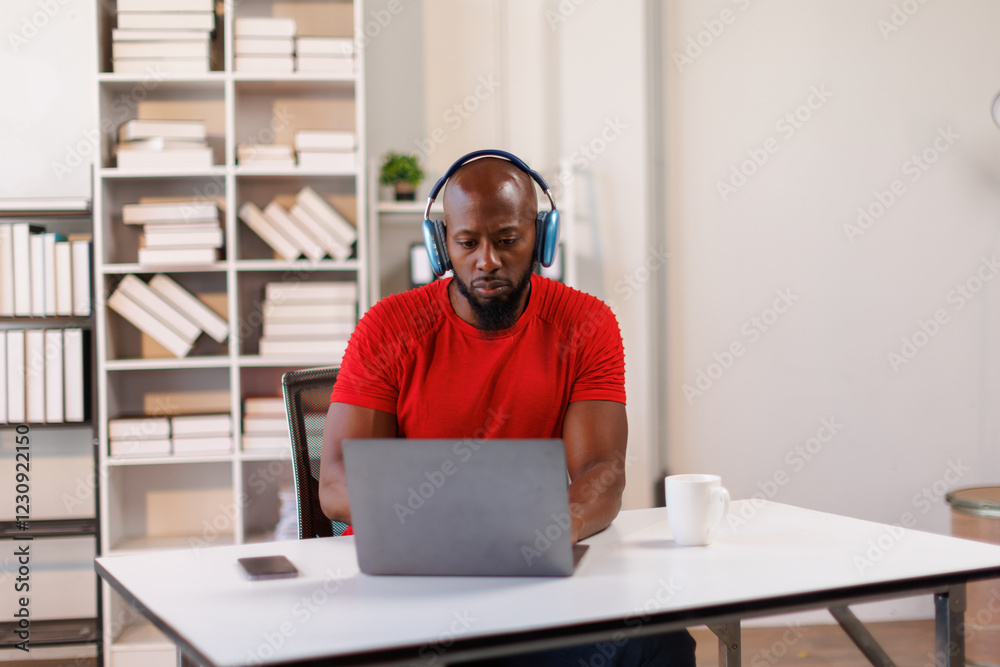 Fototapeta premium African American freelancer business man wearing headphones, enjoying working on laptop at workplace office.