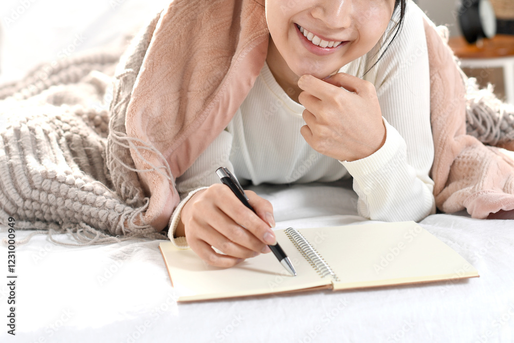 ベッドの上でメモを書き考える若い女性
ベッドの上でメモを書き考える若い女性