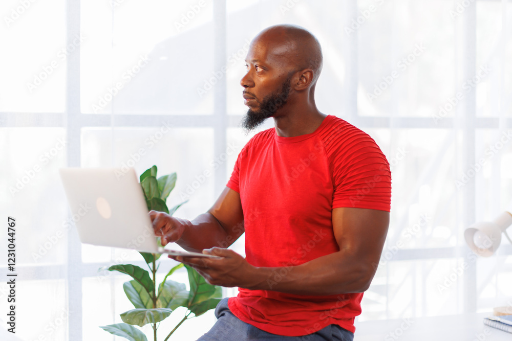 Handsome African American man standing and using a laptop to present a concept or an idea to a group of anonymous people. 