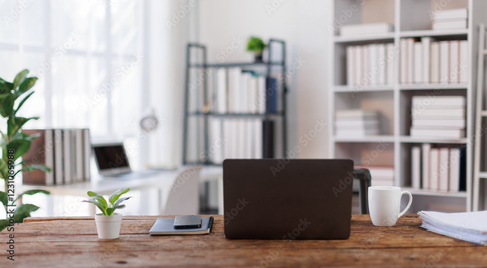 Laptop Computer, notebook, office space ,and eyeglasses sitting on a desk in a large open plan office space after working hours Laptop Computer, notebook, office space ,and eyeglasses sitting on a desk in a large open plan office space after working hours