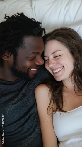 Mixed couple, white woman and black man smiling at each other in bed. Vertical photography (9:16)