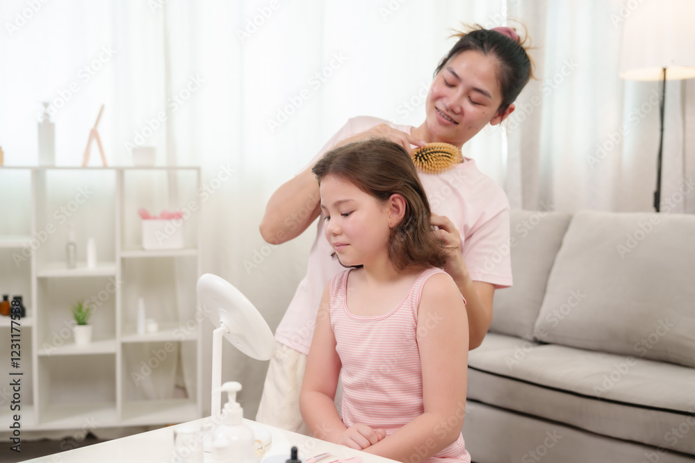Happiness of Caucasian daughter and Asian mother sharing a bonding moment. Mother brushing daughter's wavy hair while sitting together in a cozy home environment with beauty products. Happiness of Caucasian daughter and Asian mother sharing a bonding moment. Mother brushing daughter's wavy hair while sitting together in a cozy home environment with beauty products.