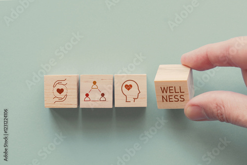 Hands holding wooden cube blocks with wellness icons, positive mental health, life balance concept.