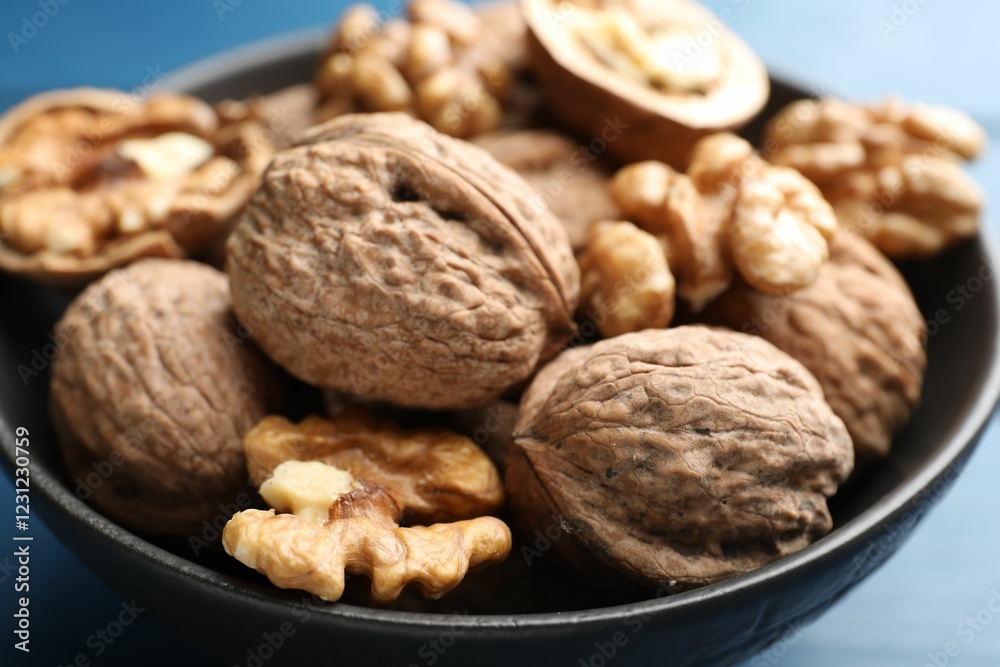 Fresh walnuts in bowl on blue table, closeup Fresh walnuts in bowl on blue table, closeup