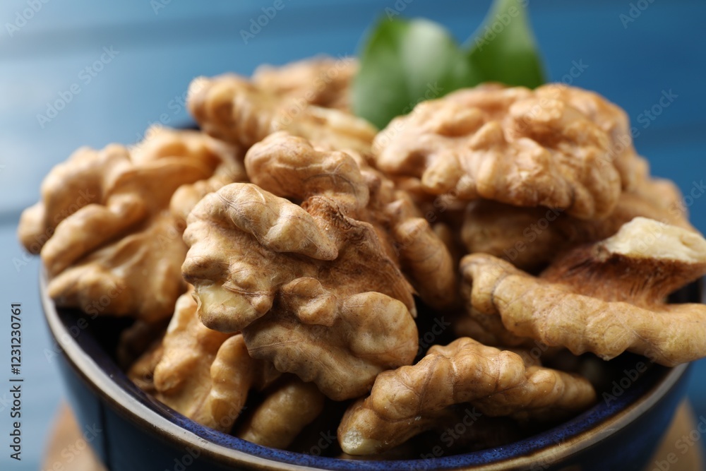 Fresh walnuts in bowl on blue table, closeup Fresh walnuts in bowl on blue table, closeup