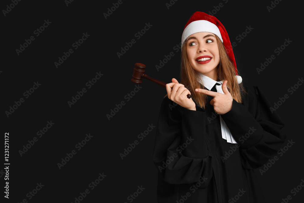 Young female judge in Santa hat pointing at something on black background Young female judge in Santa hat pointing at something on black background