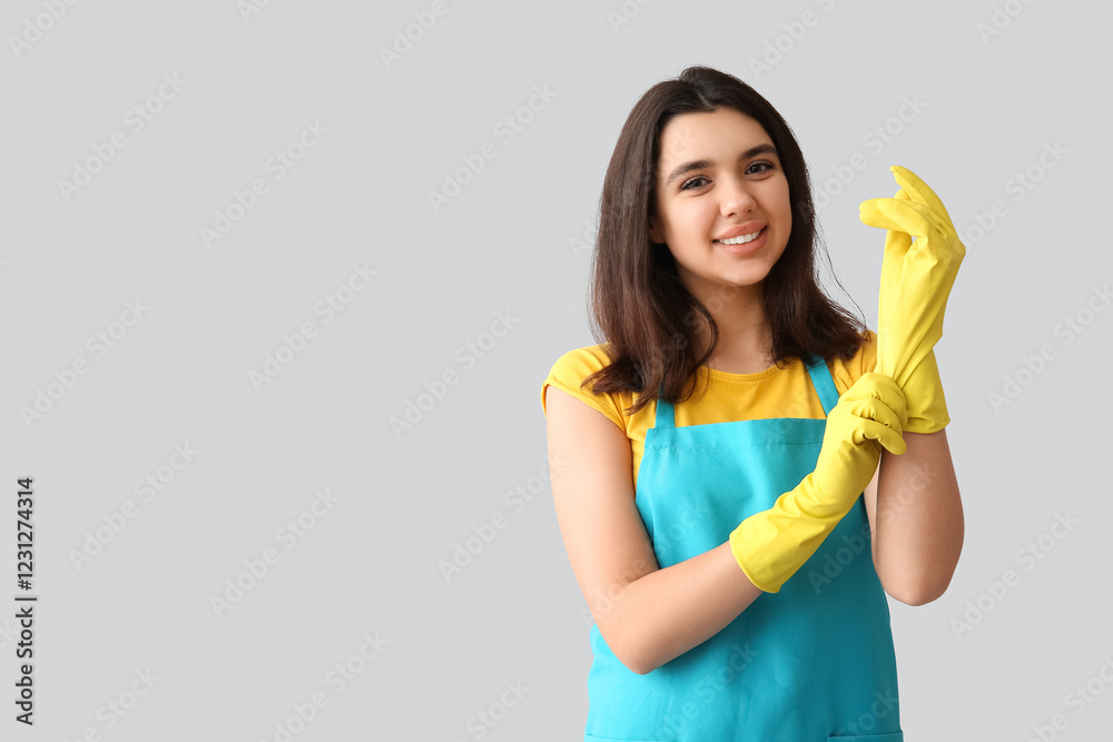 Young woman with rubber gloves on grey background Young woman with rubber gloves on grey background