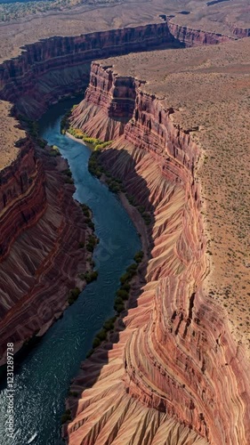 A winding canyon river seen from above, carving through layers of brightly colored striated rock.
