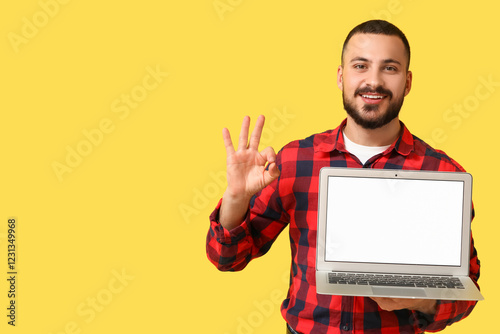 Young man with blank laptop...