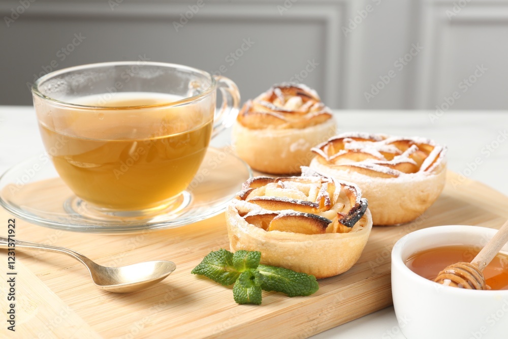 Freshly baked apple roses with mint, honey and tea on table, closeup Freshly baked apple roses with mint, honey and tea on table, closeup