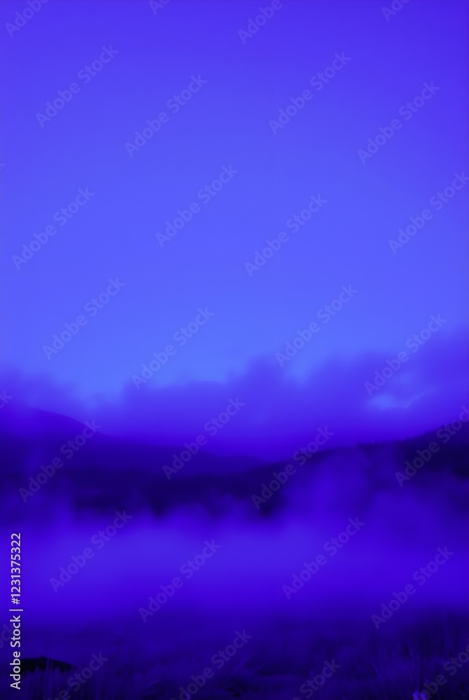 Fototapeta premium A vivid blue hue dominates the landscape, with misty clouds hovering over distant hills. The gradients of color create a serene and ethereal atmosphere.