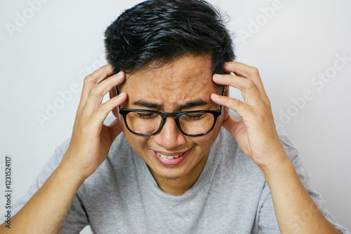 Asian young upset depressed man sitting alone in living room at home. Attractive unhappy male feeling very sad, lonely and frustrated with life problem think of money debt, budget loss, bankruptcy.