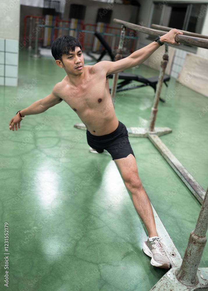 Fototapeta premium Asia young man warm up or exercising on parallel bars at gym 