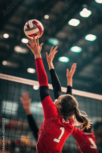 Volleyball match in indoor arena with players reaching for ball, teamwork, competition and athletic performance captured during sports event. Excitement and energy.