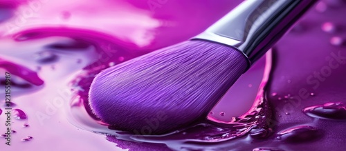 Vibrant purple cosmetic brush resting in glossy purple liquid alongside lip gloss showcasing rich textures and bold colors in beauty composition photo