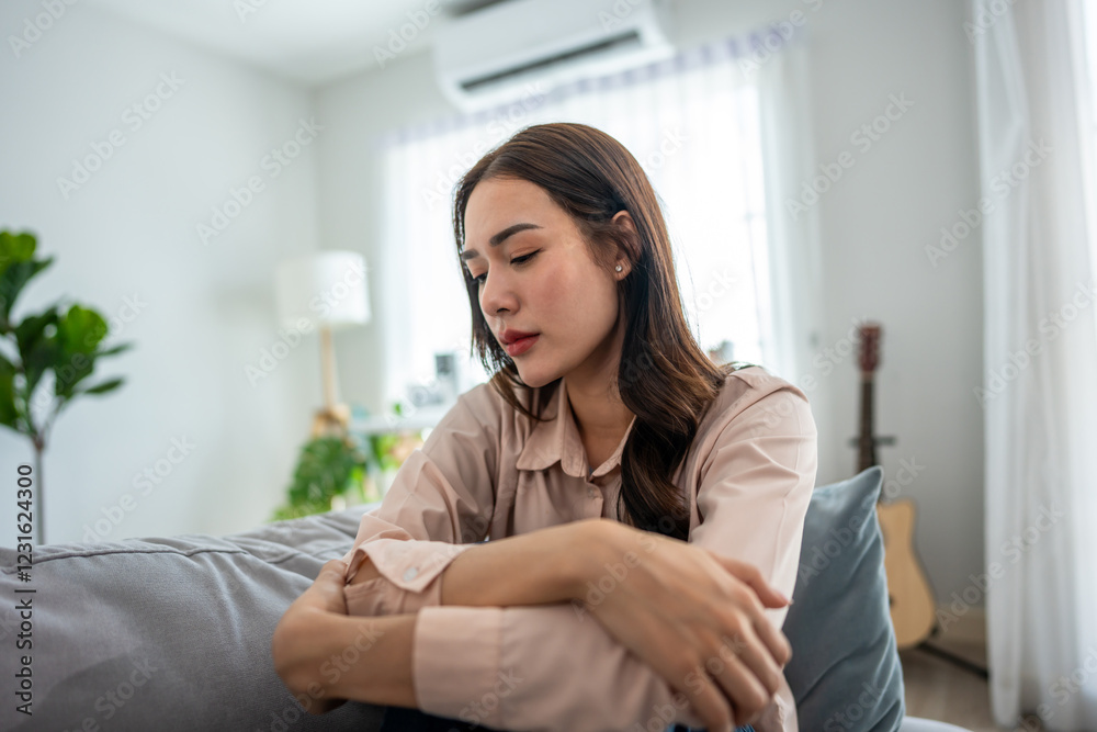 Asian upset depressed woman sitting alone on sofa in living room at home. Asian upset depressed woman sitting alone on sofa in living room at home.