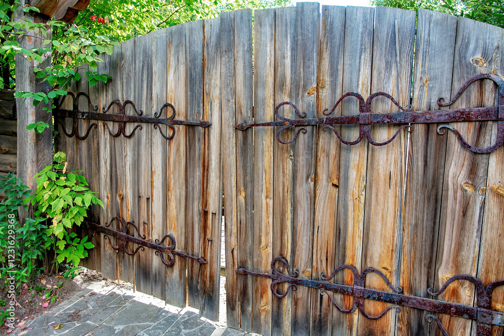 Rustic wooden gate adorned with iron hardware in a lush garden reveals a hidden sanctuary
