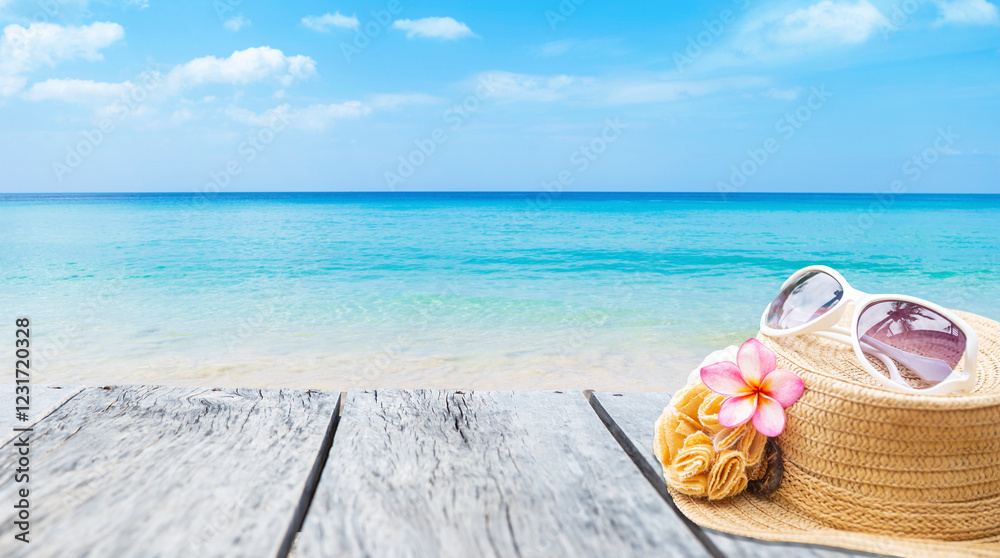 Obraz premium Jute hat with sunglasses and plumeria flower on wooden table with space on tropical beach background, summer outdoor day light, summer beach background