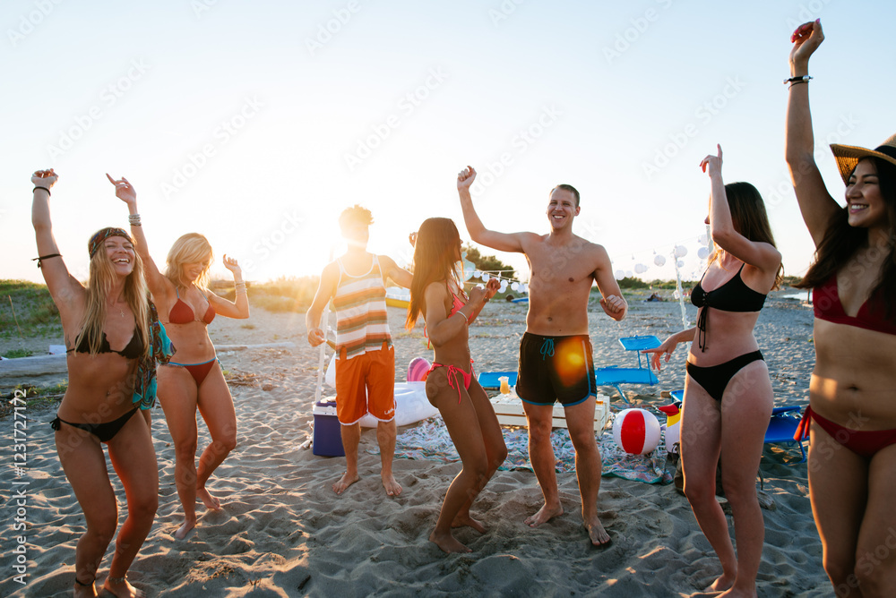 Group of friends making party on the beach at sunset time Group of friends making party on the beach at sunset time