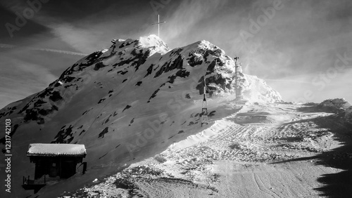 Snowy mountain in black and white with a cross on the summit