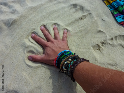 Obraz na płótnie Hand with colorful friendship bracelets and wristbands making an imprint in pristine white sand on Great Keppel Island beach, Queensland, Australia. Perfect palm impression against bright sunlit beach w salonie