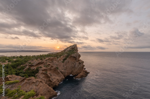 Lever de soleil sur les falaises de Cassis, offrant une vue spectaculaire sur la mer Méditerranée. Lumière douce et ciel nuageux créent une ambiance apaisante sur ce paysage sauvage et préservé.