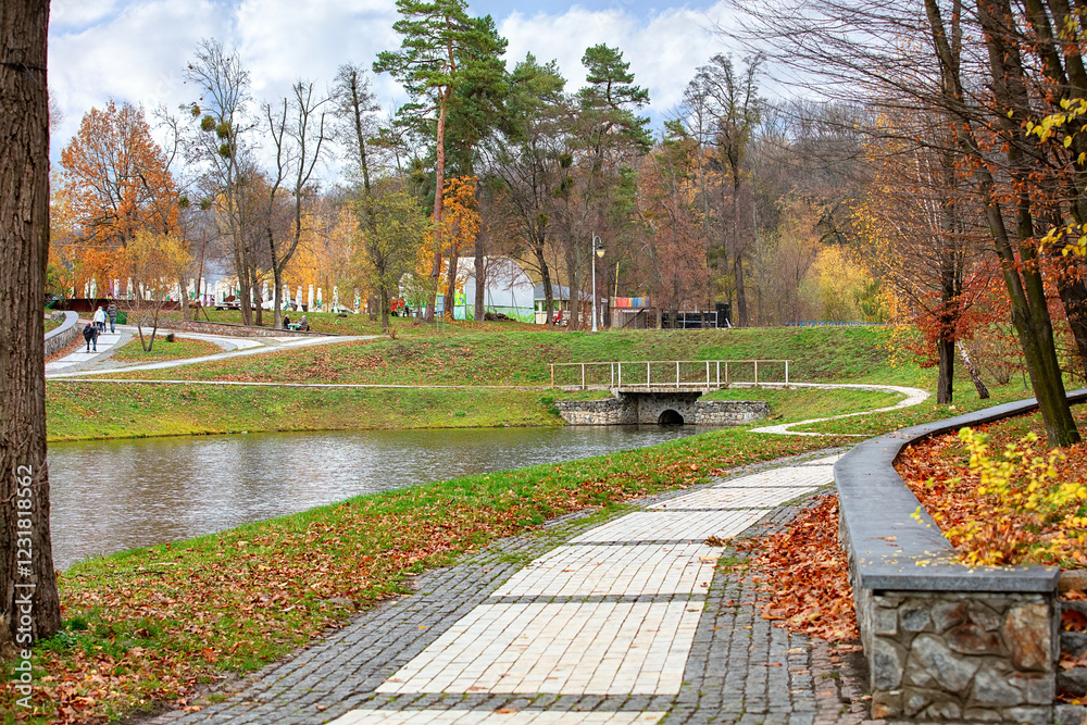 Vibrant autumn stroll along the tranquil pond in a picturesque park setting